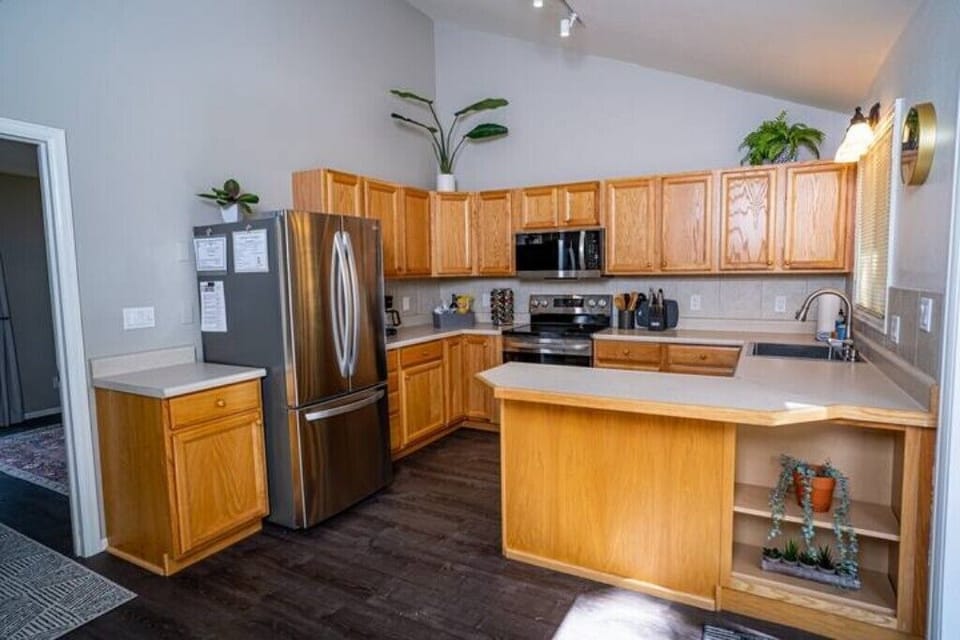 Vaulted ceilings in fully stocked kitchen with stainless steel appliances. 