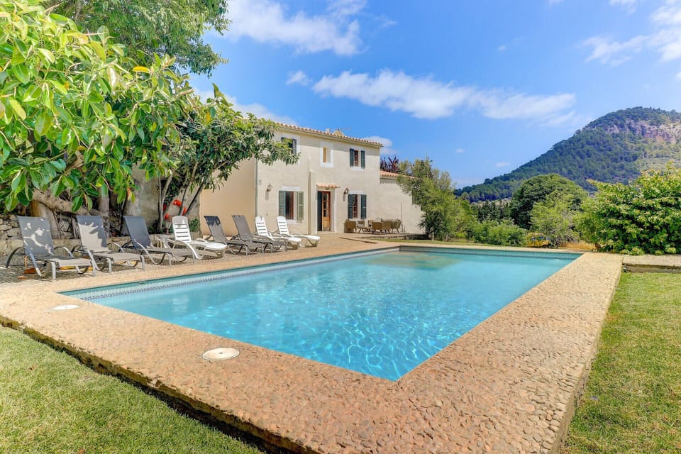 Private swimming pool at  Casa Colonya, surrounded by garden and sun loungers, with open views of the mountains and the main house.