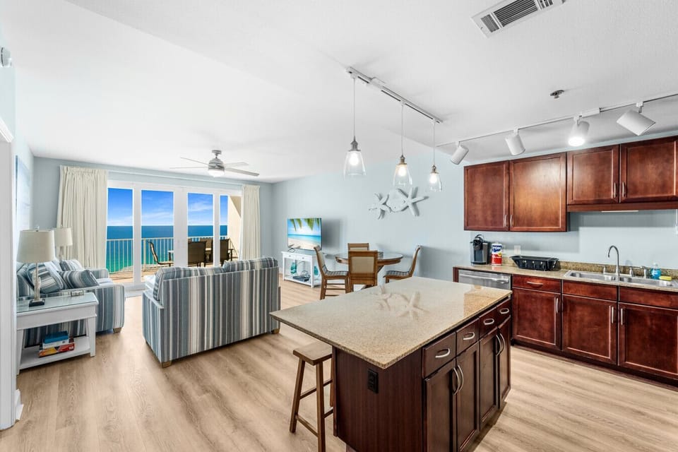 Experience open-concept living with a spacious kitchen, dining area, and comfortable seating that leads to a private balcony showcasing breathtaking ocean views