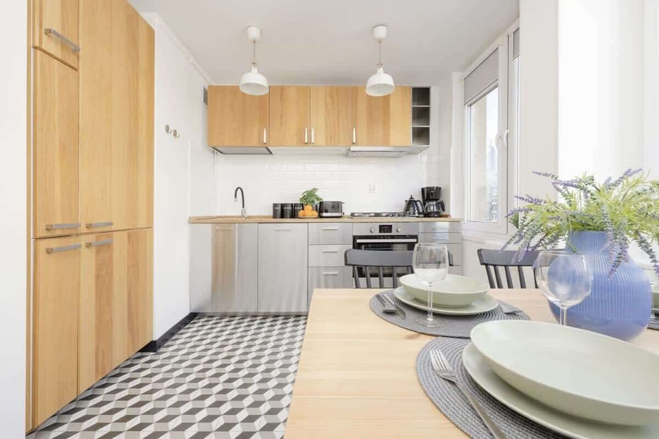 A spacious kitchen with wooden cabinets, white countertops, and a geometric-patterned floor, blending modern and classic elements.

