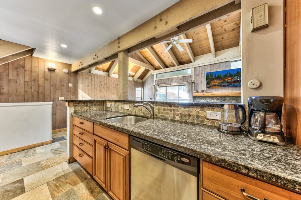 This rustic kitchen features granite counters, stainless appliances, and coffee station beneath exposed beams - perfect for mountain morning meals.