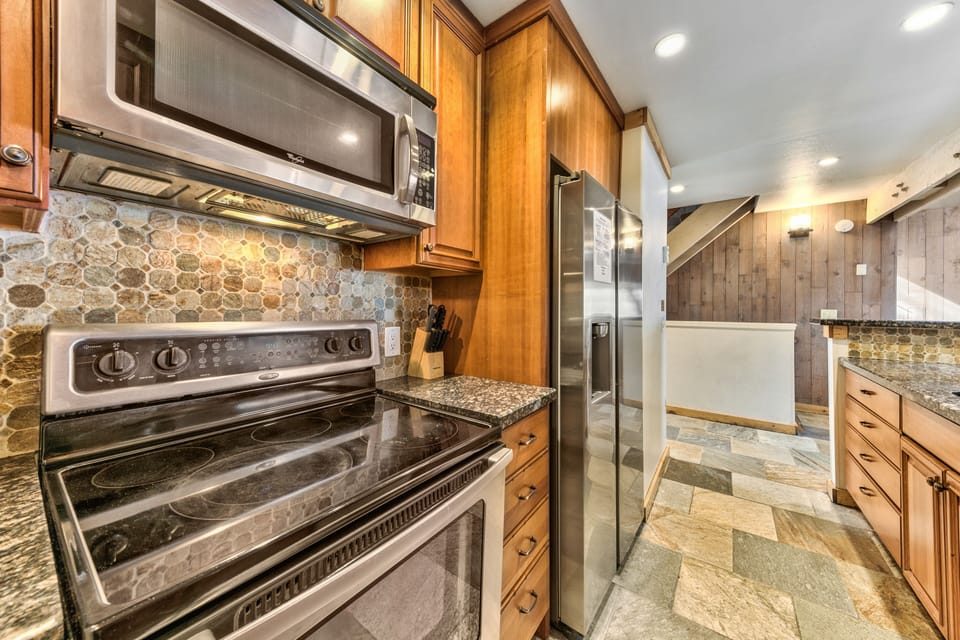 This gourmet kitchen features granite countertops, stainless steel appliances, and warm wood cabinetry for memorable meal preparation.