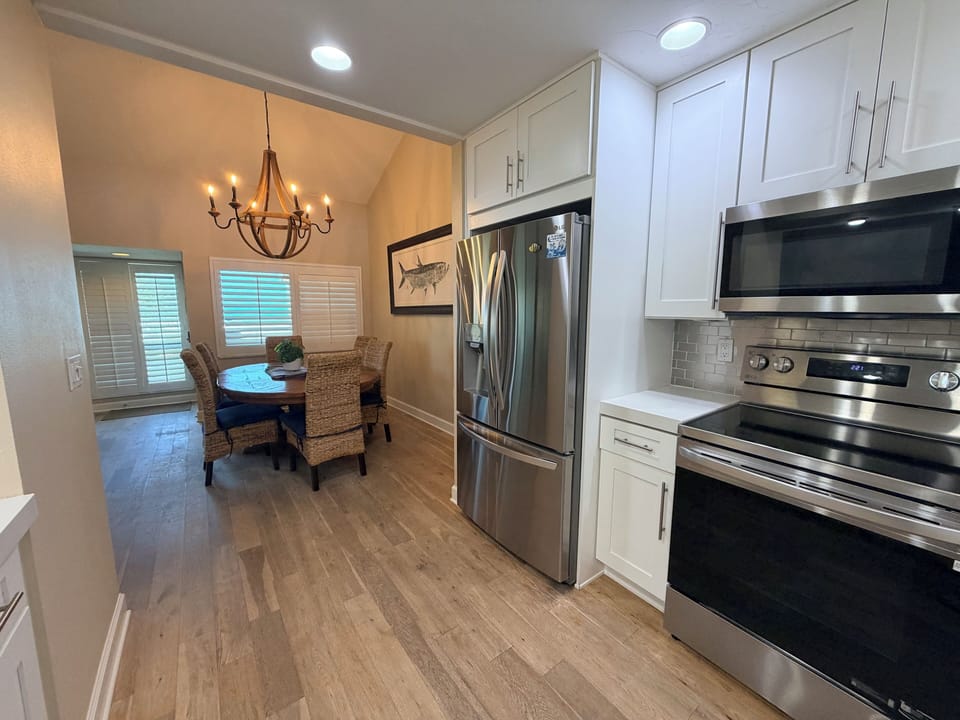 Step into your bright, modern kitchen with stainless appliances, white cabinetry, and open flow to the warm dining space—perfect for preparing meals together.