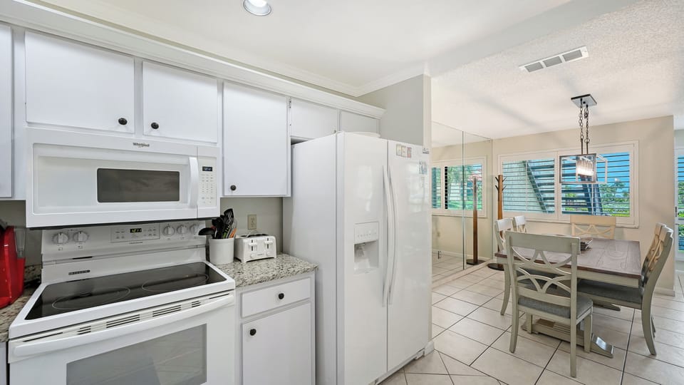 Your bright, fully equipped kitchen opens to the dining area where natural light floods in, setting the scene for easy meals and relaxed mornings with your first cup of coffee.