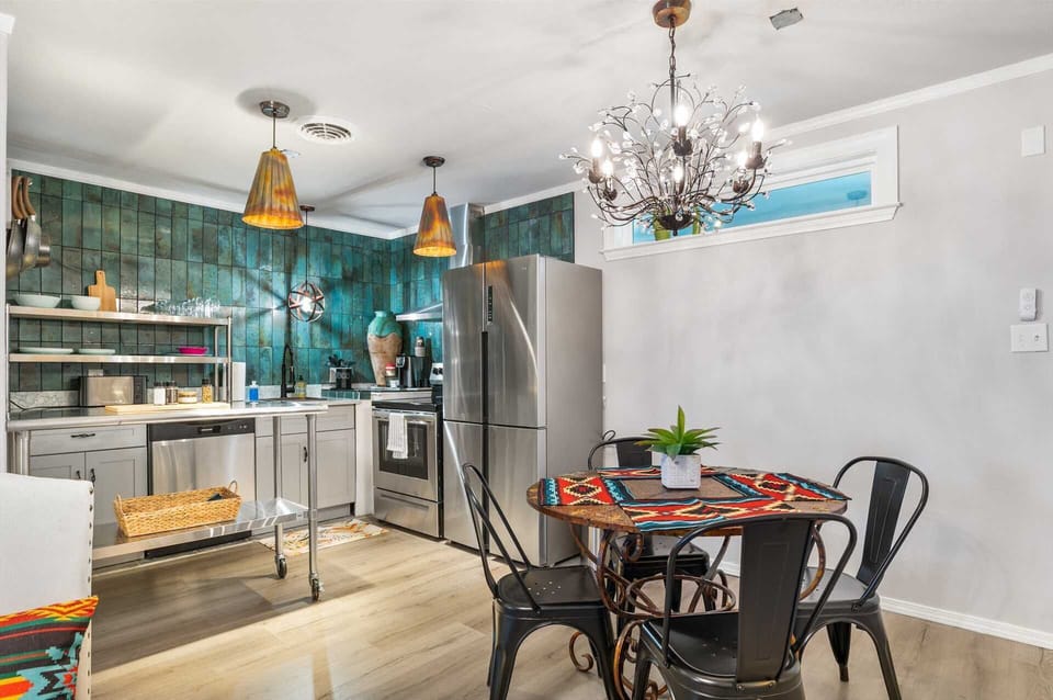 Stylish and vibrant kitchen-dining space featuring eye-catching teal tile, warm pendant lighting, and a cozy dining nook-perfect for meals with a touch of character.