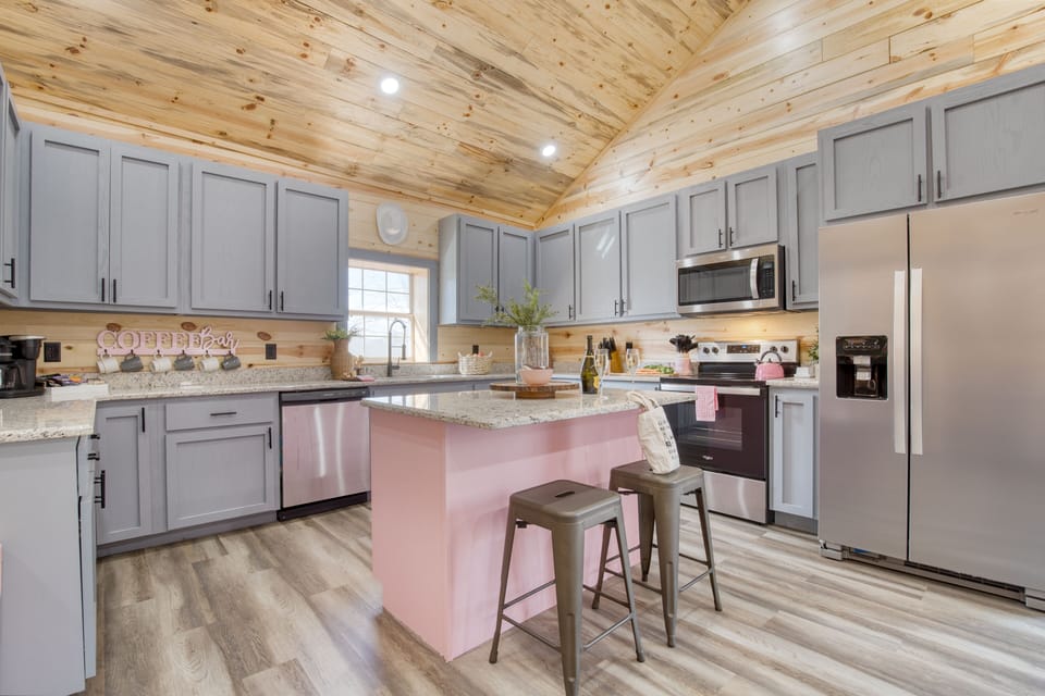 Pink-accented kitchen with a coffee bar, island seating, and plenty of space for group meals.