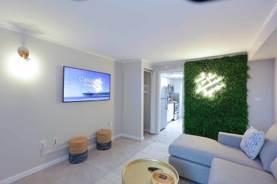 Binge your favorite shows, sip something chilled, and snap a selfie in front of the neon-lit moss wall—this living space is giving major vacation vibes with a side of style. 