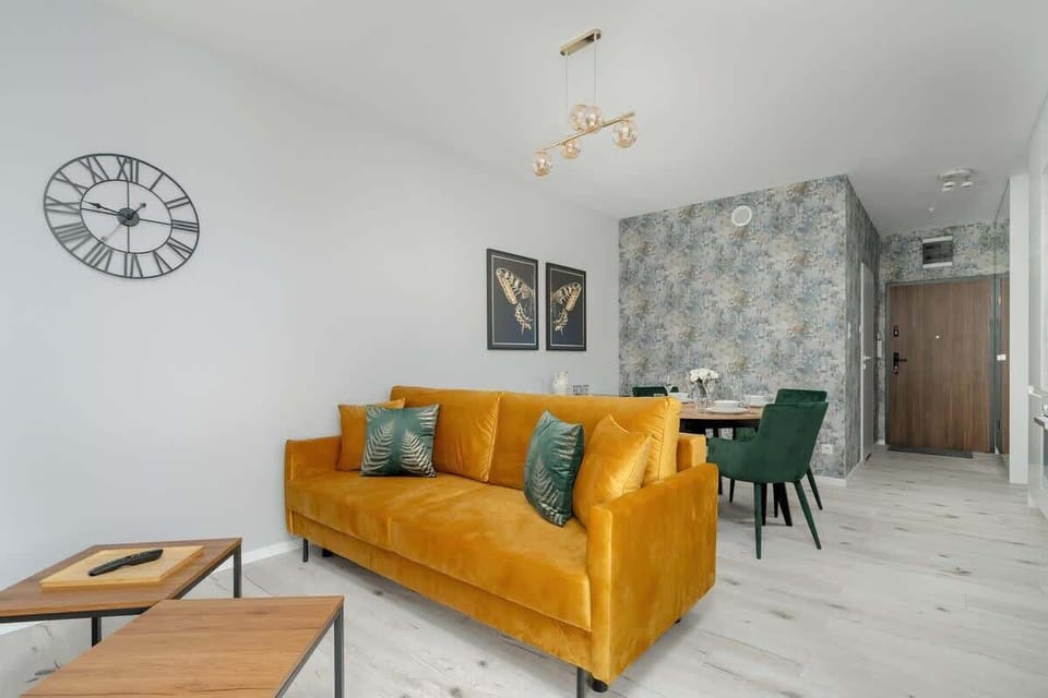 Another angle of the living area, highlighting a stylish round coffee table, a decorative wall clock, and elegant lighting.

