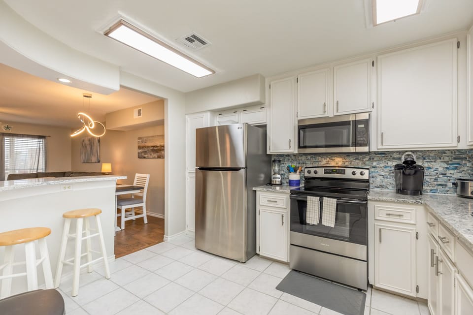 Your bright, modern kitchen awaits with stainless steel appliances, granite counters, and stylish backsplash—perfect for whipping up morning coffee.