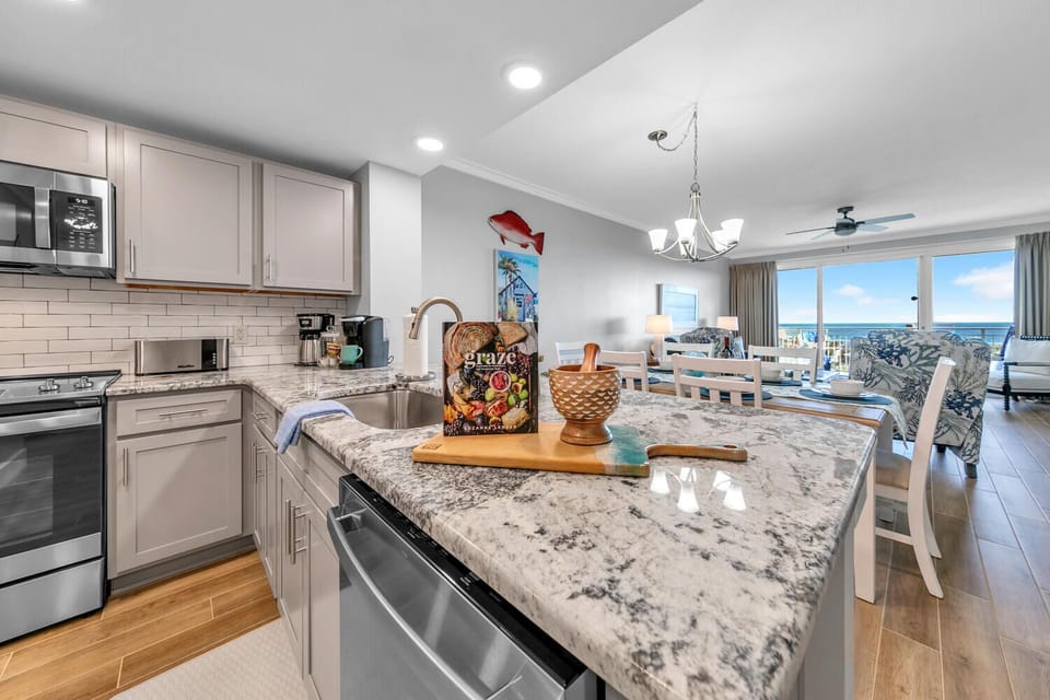 Your modern kitchen flows seamlessly into the living area, with granite counters and ocean views creating the perfect space for coastal cooking.