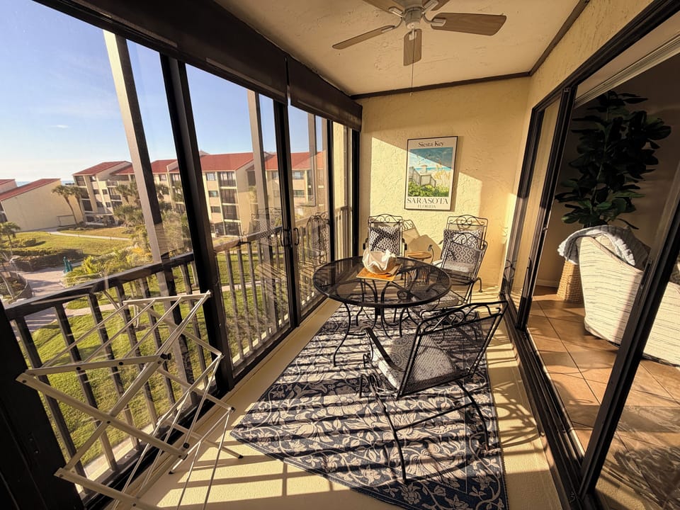Relax on your private screened balcony with outdoor dining furniture, enjoying peaceful views of the landscaped grounds and surrounding buildings.