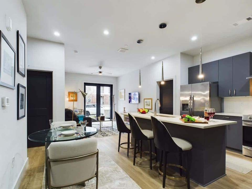 Fully equipped kitchen with stainless steel appliances, basic cooking essentials, toaster, coffee machine, kitchen island seating, and breakfast table for 2.