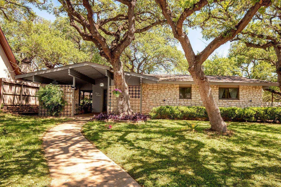 Escape to this mid-century modern stone home nestled on a spacious lot, surrounded by majestic oak trees, offering a tranquil retreat from the bustle.
