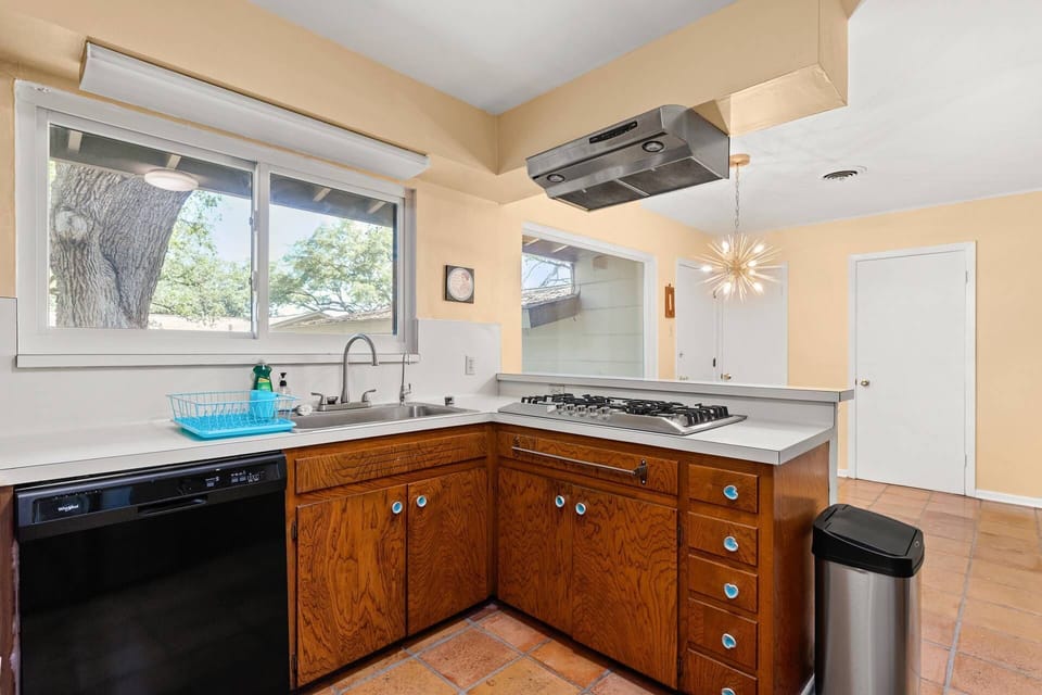 Take a journey back in time to the 1960s with the authentic kitchen featuring vintage wood cabinets, complemented by a classic gas stovetop range.