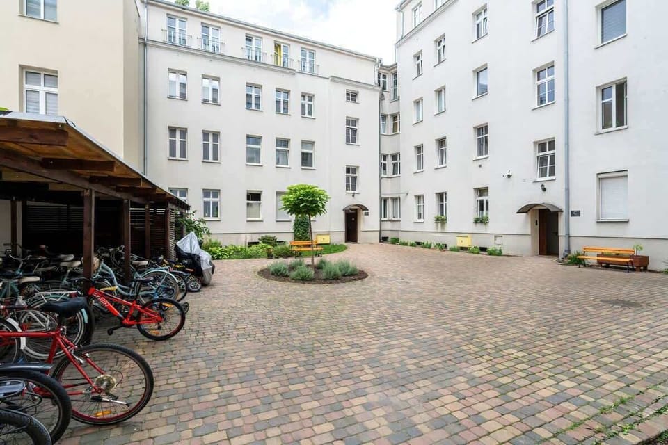 A charming courtyard with cobblestone paving, bicycle parking, and lush greenery, offering a peaceful communal space.

