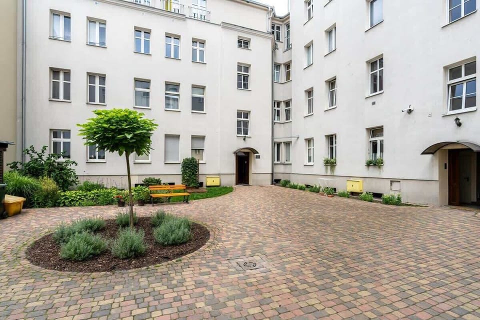 A picturesque courtyard with cobblestone paths, green plants, and a well-maintained historic building exterior.

