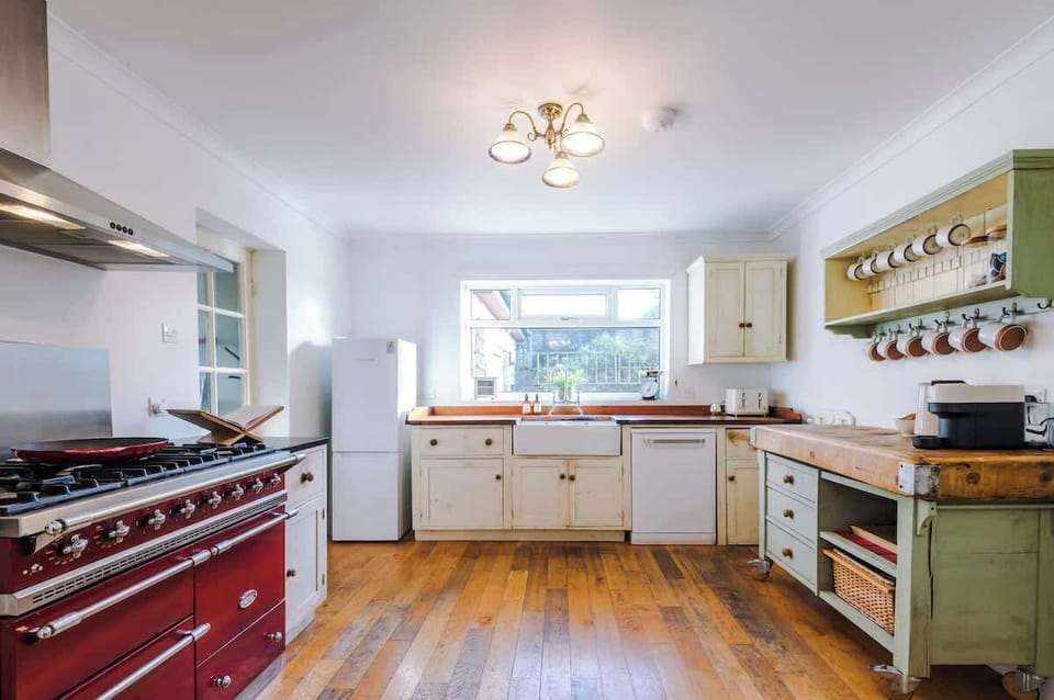 The heart of the home—a spacious country kitchen featuring a massive range cooker, Belfast sink, and a large dining table perfect for group feasts.