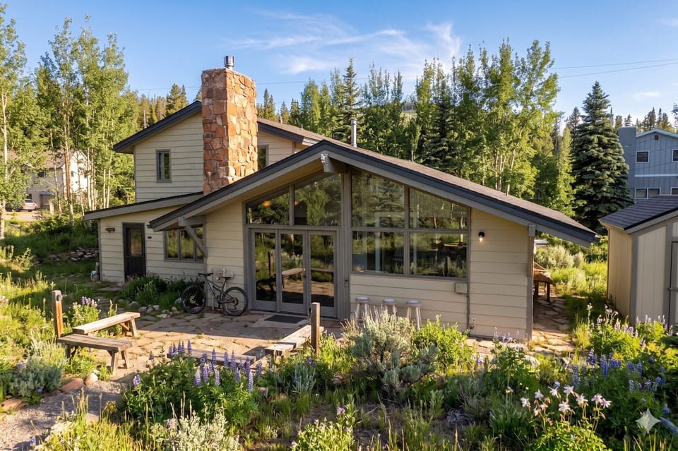 A charming mountain retreat with a striking stone chimney, surrounded by wildflower gardens and tall pines—your peaceful escape near the slopes.