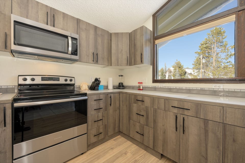 Your fully-equipped kitchen features modern appliances and plenty of counter space for preparing meals while enjoying tree-lined views.