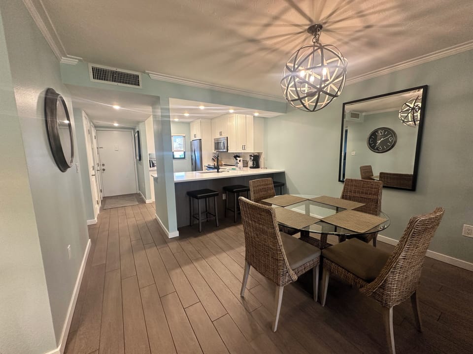 Your open-concept dining area features stylish wicker chairs and a stunning orb chandelier, perfectly connecting to the fully-equipped kitchen.
