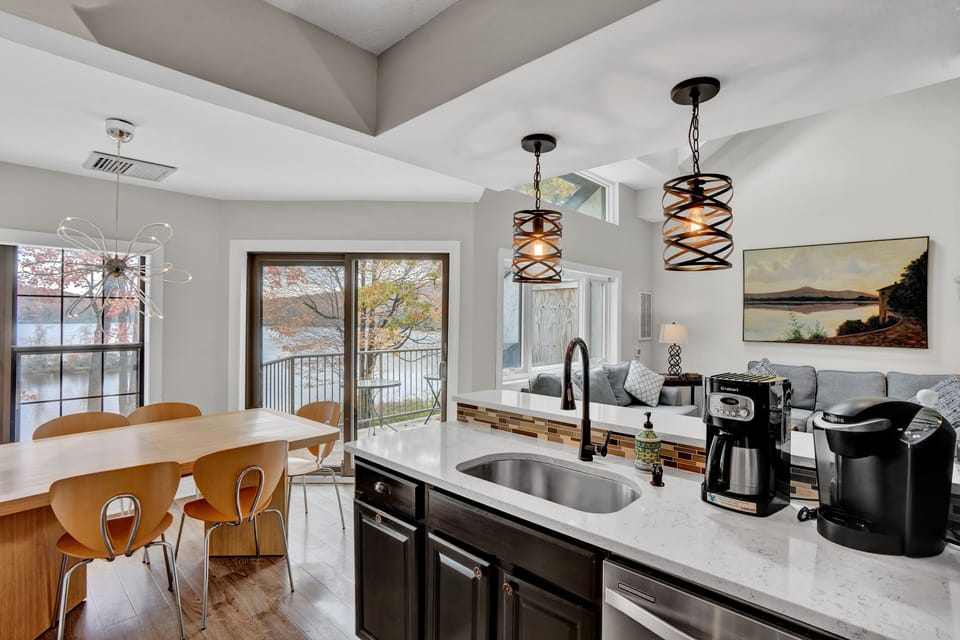 View of dining area, living room, and lake from modern kitchen