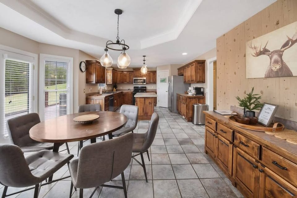 Spacious kitchen and dining area with rustic wood cabinetry and natural light from large windows.