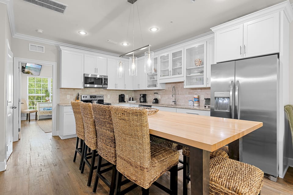 Fully equipped kitchen with granite countertops, stainless steel appliances, and a butcher block island with seating for four.