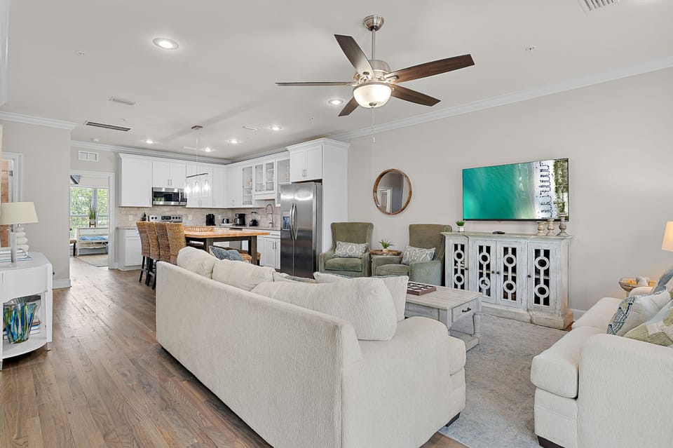 Open-concept living and dining with hardwood floors, plush seating, and a fully equipped kitchen — perfect for gathering after a day at the beach.