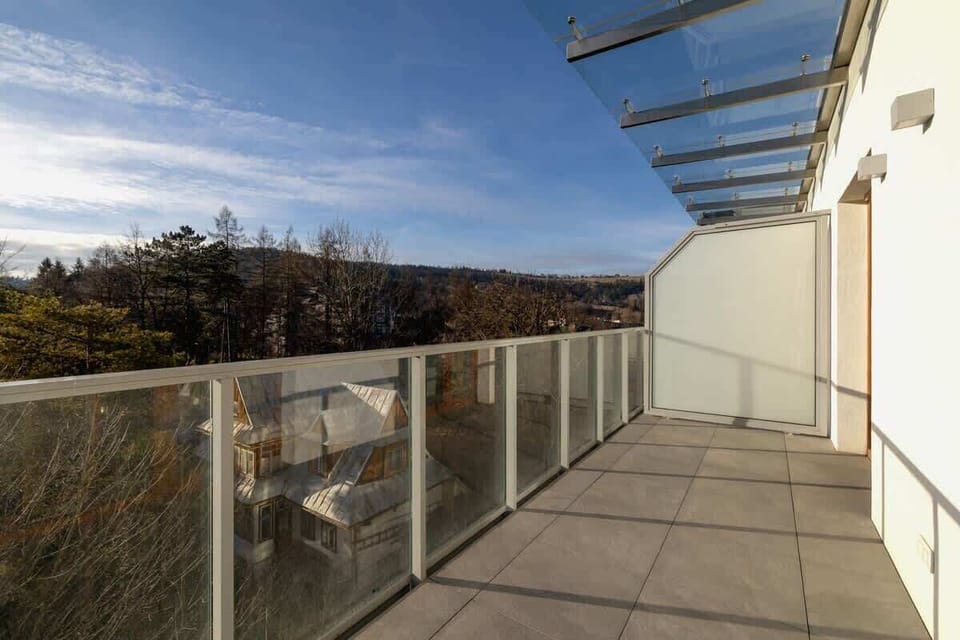 Another view of the balcony, emphasizing the glass railings, spacious layout, and breathtaking natural surroundings.

