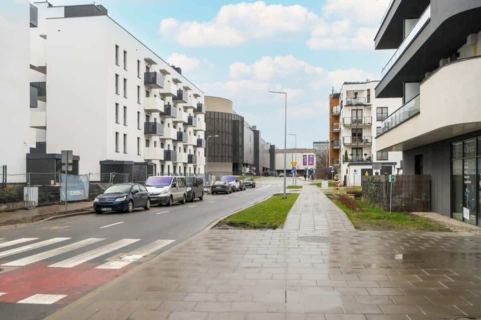 Another street view showcasing a modern neighborhood with white apartment buildings, a bicycle lane, and a pedestrian walkway, emphasizing a well-planned and accessible area.







