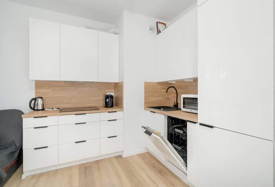 Another angle of the kitchen, showcasing white cabinets, a wooden backsplash, and integrated appliances for a streamlined look.

