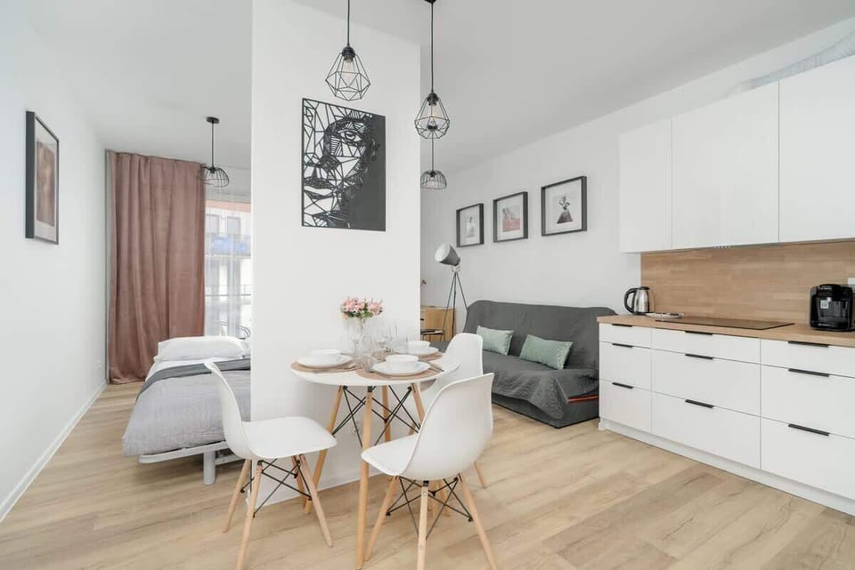 A bright kitchen and dining area with white cabinetry, modern appliances, and a spacious wooden countertop for an airy and open feel.

