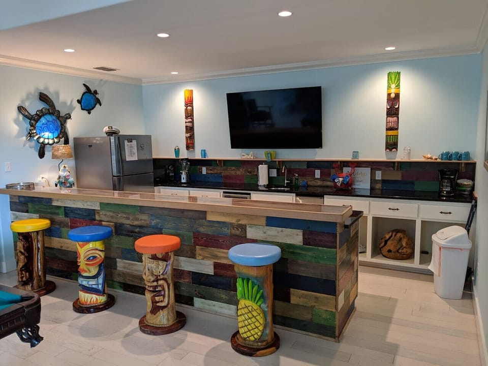 Custom tiki bar with colorful stools and flat-screen TV