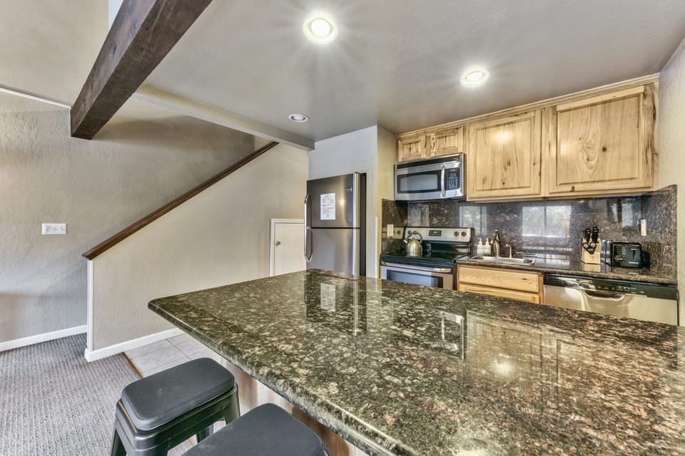 Cook memorable meals on gleaming granite counters in your fully equipped kitchen, featuring rustic wood cabinets and modern appliances.