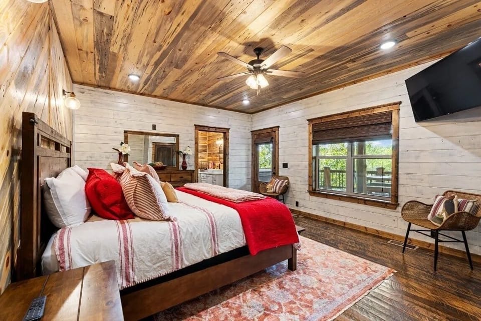 Unwind in luxury at our cabin retreat, where a king bed, spacious ensuite bathroom, and stone-tile shower with a soothing rain head and waterfall feature await. Step out onto the covered deck for a relaxing dip in the hot tub