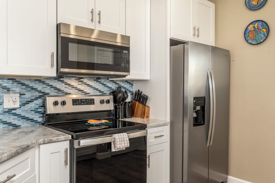 Your fully-equipped kitchen features stainless steel appliances and stylish blue tile backsplash, perfect for preparing memorable meals during your stay.