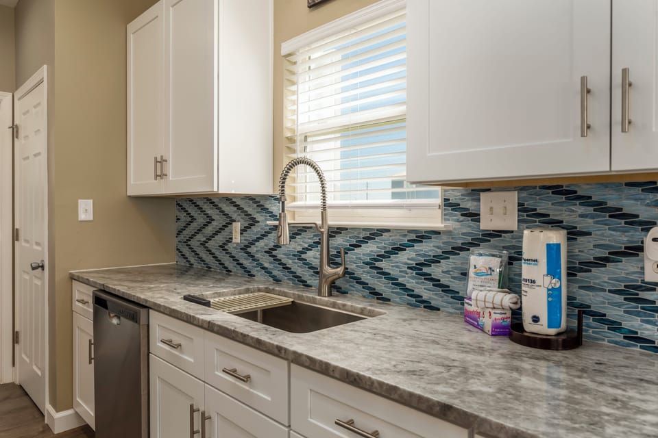 Your fully equipped kitchen features granite counters, modern appliances, and a stunning mosaic backsplash perfect for preparing meals.