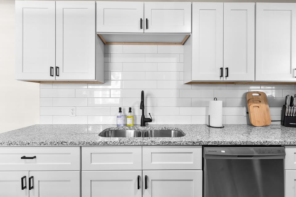 Your fully equipped kitchen features granite countertops, white subway tile backsplash, and modern appliances for preparing memorable meals.