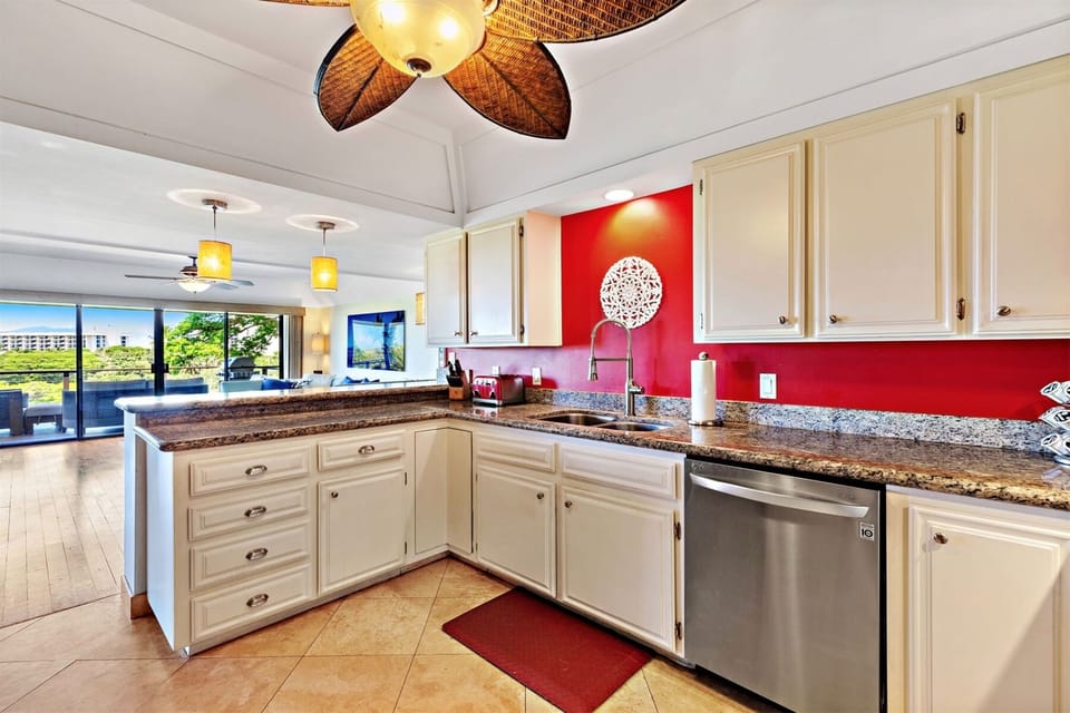 Striking kitchen with beautiful granite counter tops and built in stove top, and ceiling fan, as well as a full-size dishwasher.