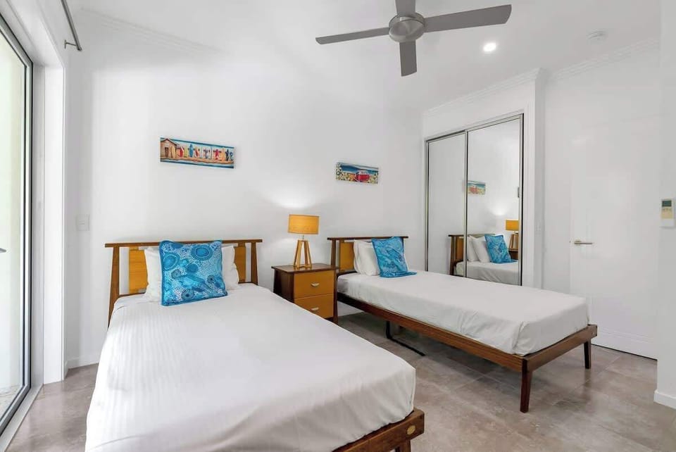 The second bedroom features two comfortable single beds, mirrored wardrobes, and air-conditioning providing a cosy space for relaxation.