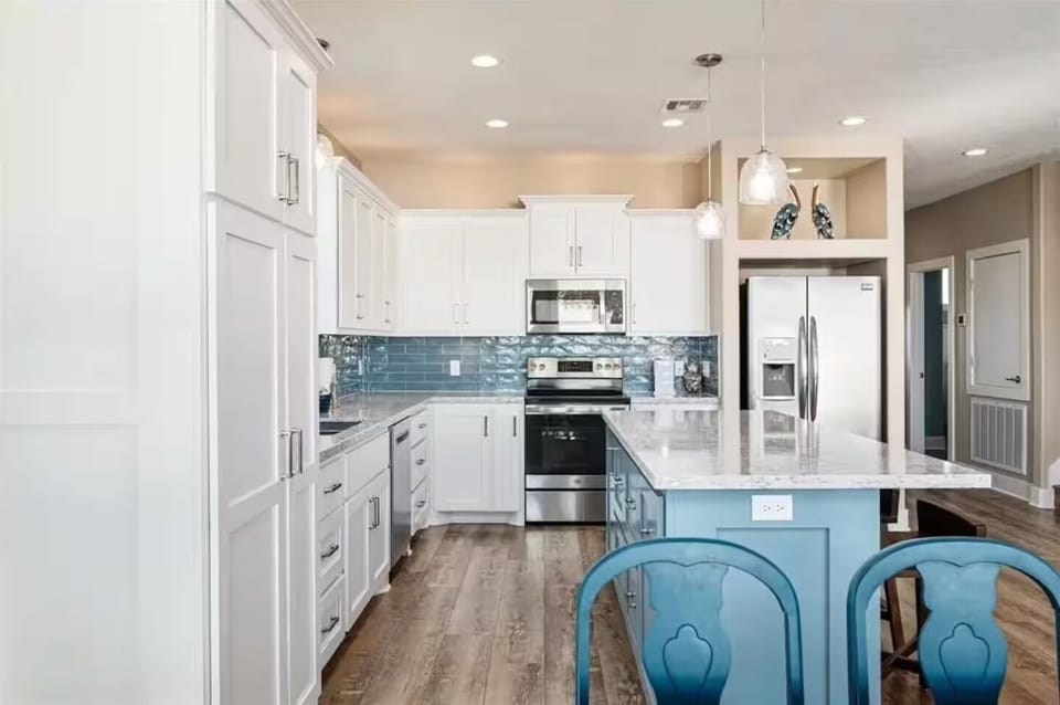 Bright modern kitchen with large island, stainless appliances, and coastal charm