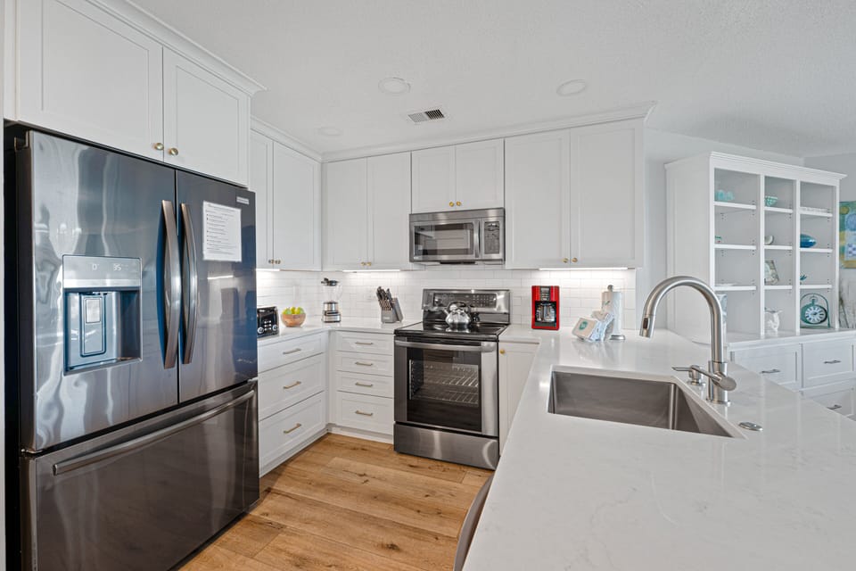 This bright, updated kitchen features crisp white cabinetry, granite countertops, stainless steel appliances, and a spacious breakfast bar with seating for three.
