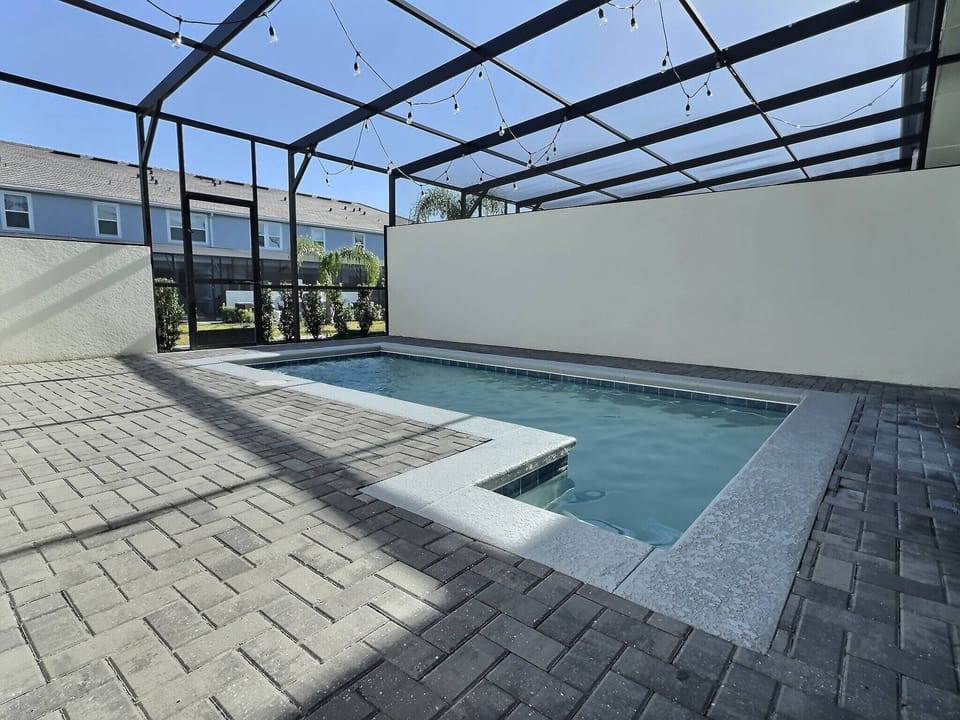 Step outside to your private oasis, where a sleek stone-accented pool invites relaxation under the blue sky. The spacious patio, framed by a stylish cage, sets the perfect scene for sunny afternoons and evening gatherings.