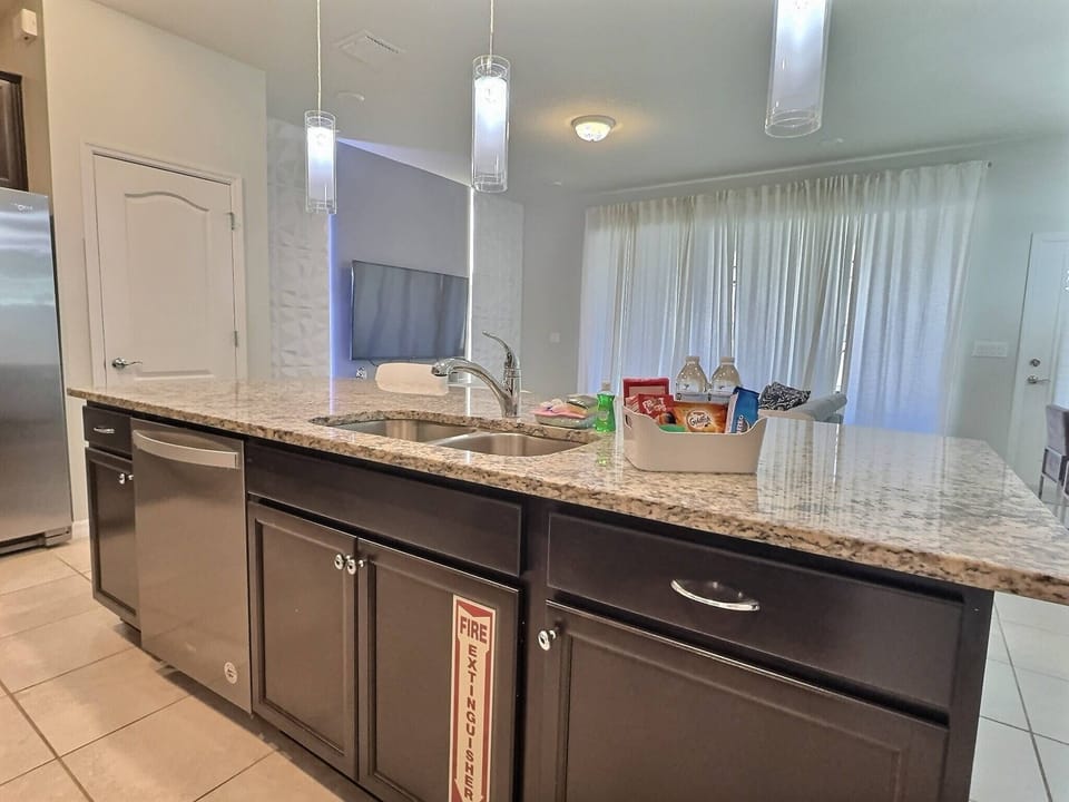 The sleek dark cabinetry beautifully contrasts with the light granite countertop, creating a stylish focal point. Pendant lighting adds warmth, while large windows invite natural light, enhancing the kitchen's inviting atmosphere.