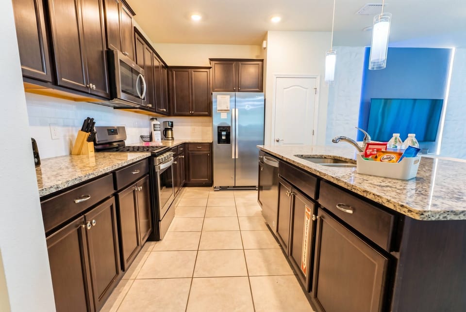 Welcome to a beautifully designed kitchen with dark cabinetry and elegant granite countertops, offering both style and functionality. Modern appliances and sleek tile flooring create an inviting space ideal for meal preparation.