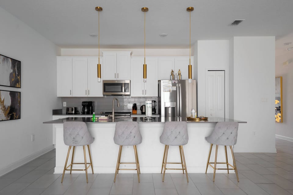 This stylish kitchen boasts a spacious island with chic gray stools, perfect for casual dining. The bright white cabinetry and stainless steel appliances create a fresh, modern vibe for your culinary adventures during your stay.