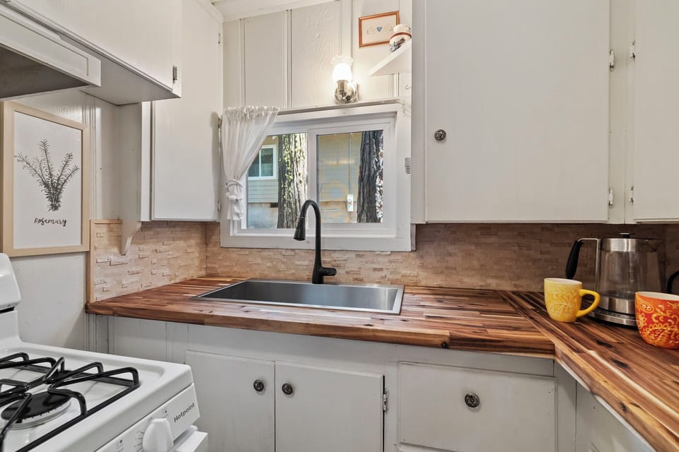 A fully stocked kitchen with stove, microwave, kettle, coffee maker, and toaster