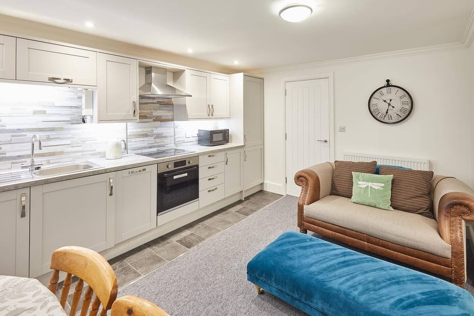 A living room sits opposite the kitchen, seamlessly connected. Soft furnishings and warm decor invite comfort and conversation, merging culinary delights with shared moments in a cozy embrace.
