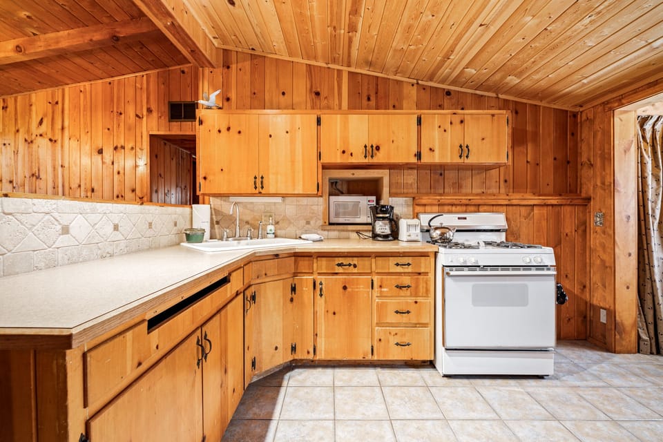 Functional kitchen w/ wraparound counters, stove & warm wood finishes throughout.