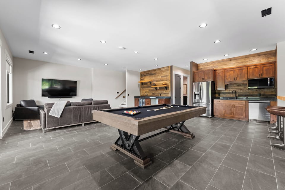 Lower Level family room with couch, TV, Pool table, wet bar and kitchenette. 